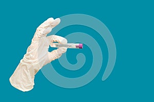 Lab experiment tube in glove handÂ Finger grip on isolated blue background with copy space